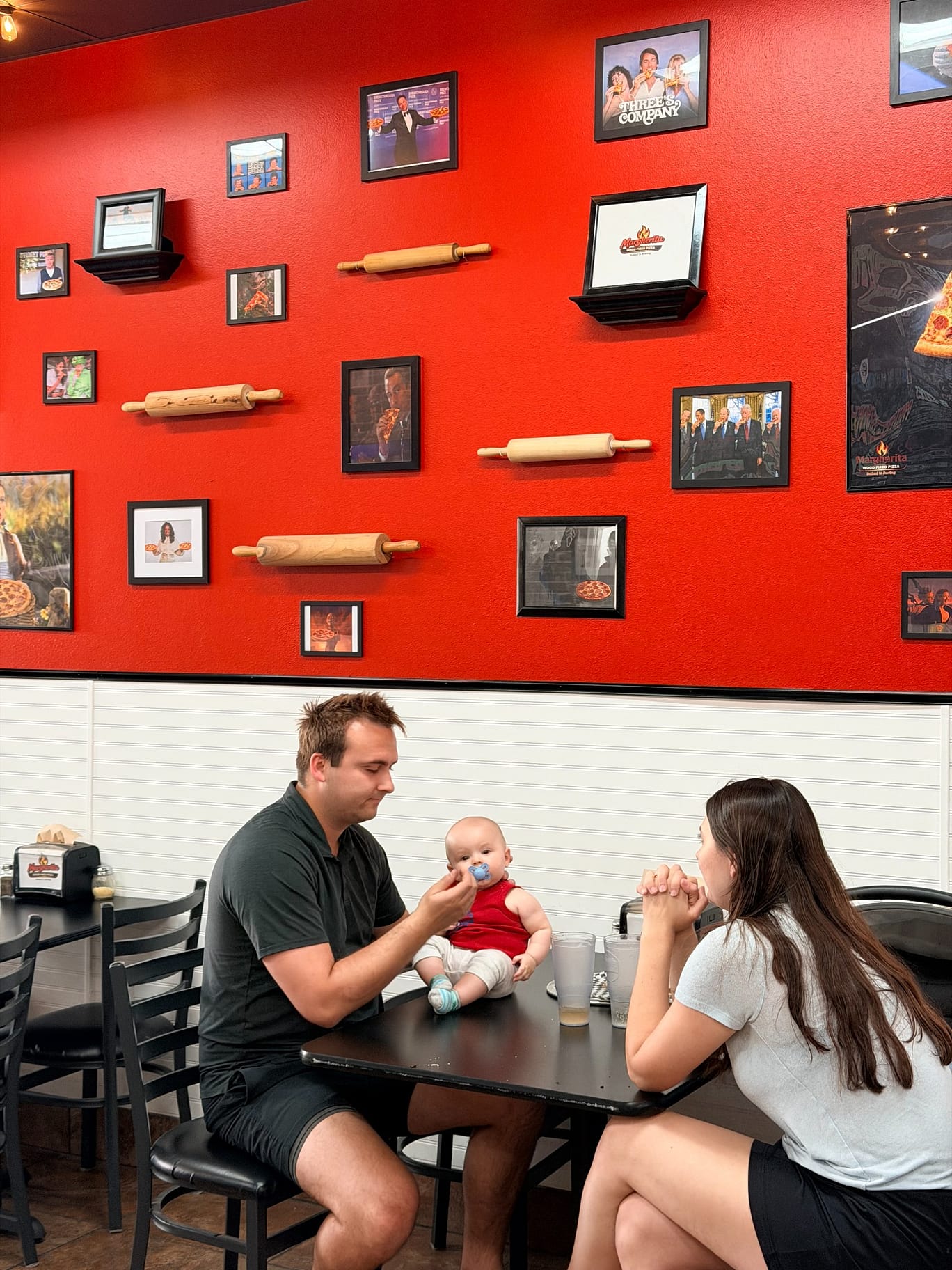 A family seated together beneath the pizza artwork at Margherita Pizza