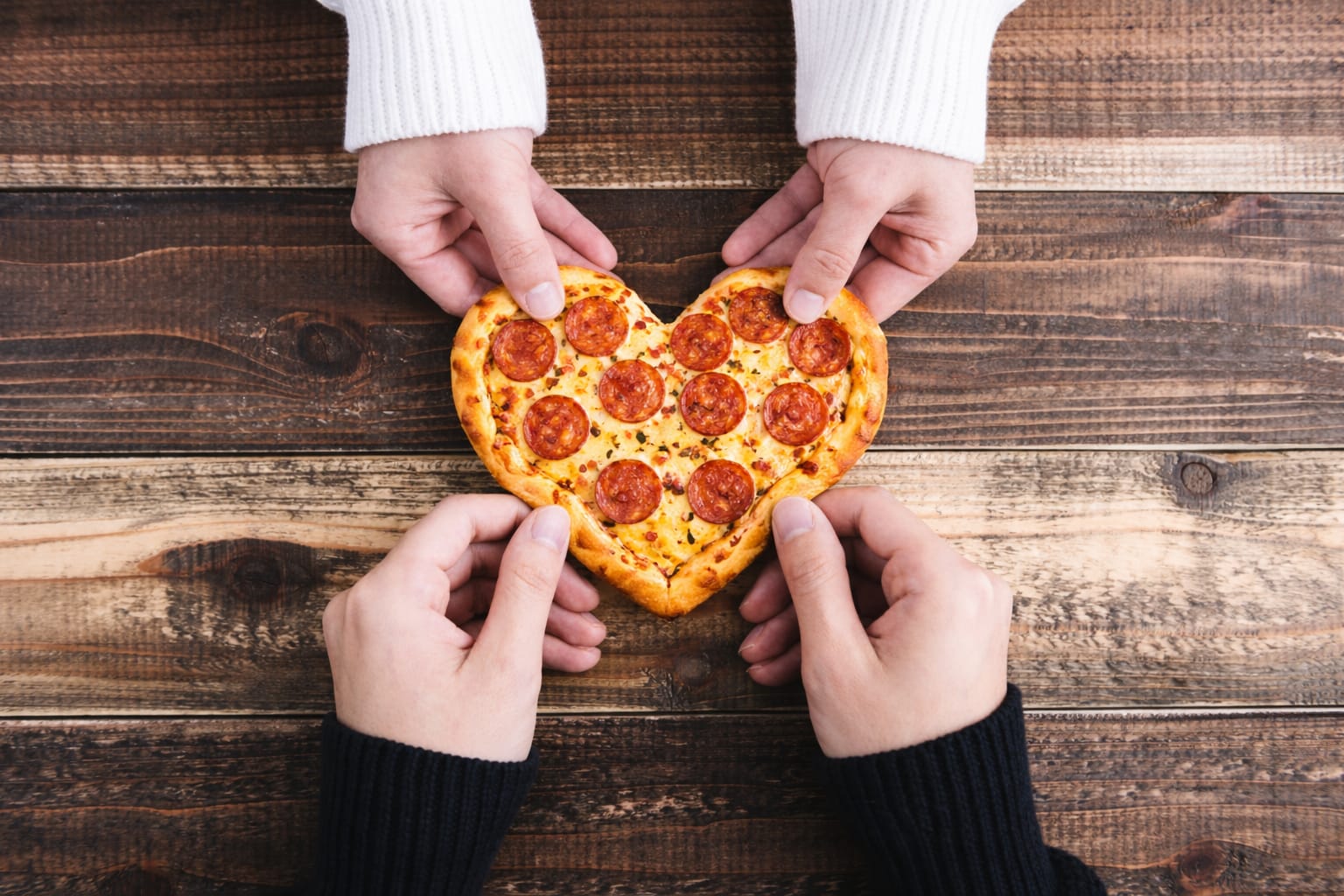 Illustration of hands sharing a heart-shaped pepperoni pizza