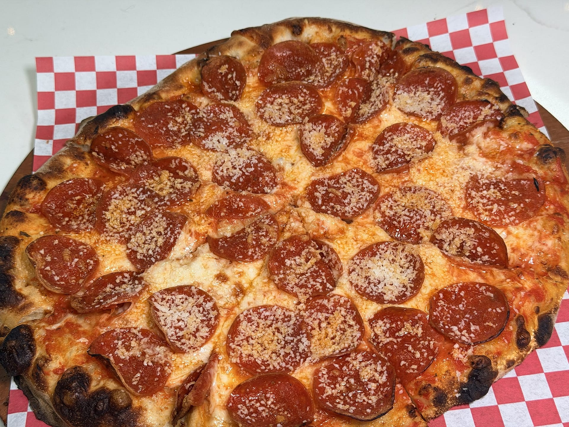 Wood-fired pepperoni pizza topped with grated pecorino at Margherita Pizza