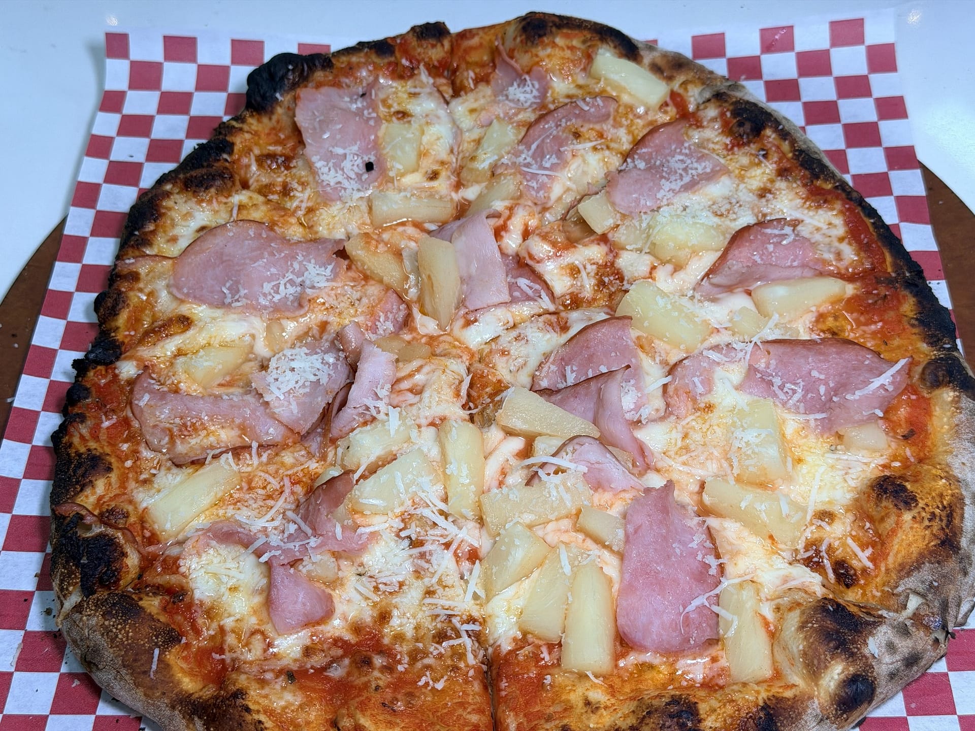 Wood-fired Hawaiian pizza topped with ham, pineapple and grated cheese